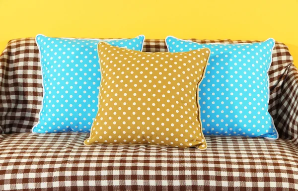 Colorful pillows on couch on yellow background — Stock Photo, Image