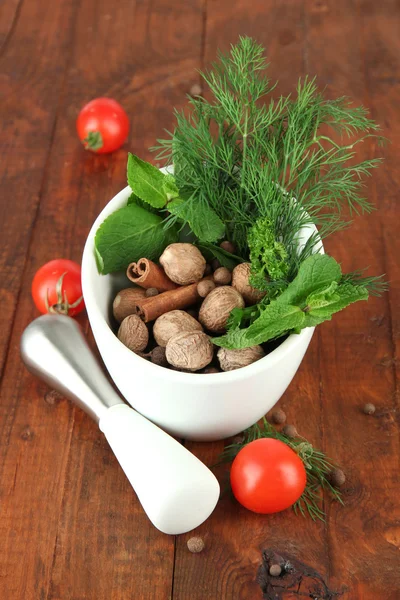 Herbes et épices en mortier céramique, sur fond bois — Photo