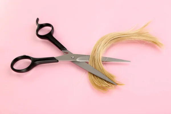 Pieces of hair cut with scissors on pink background — Stock Photo, Image
