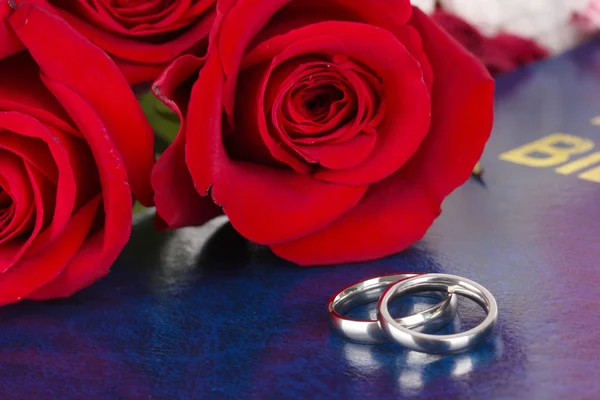 Wedding rings with roses on bible — Stock Photo, Image