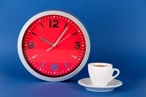 Šálek kávy a hodiny na modrém pozadí — Stock fotografie