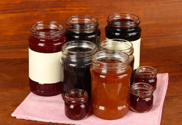 Tasty jam in banks on wooden background — Stock Photo, Image