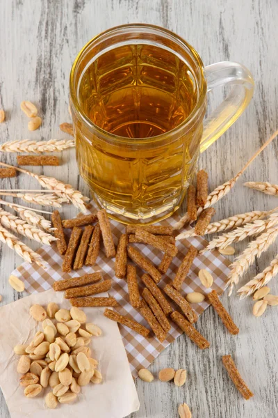 Beer in glass crunches, and nuts on napkin on wooden table — Stock Photo, Image
