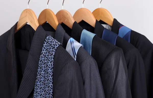 Kostymer och slipsar på galgar på grå bakgrund — Stockfoto