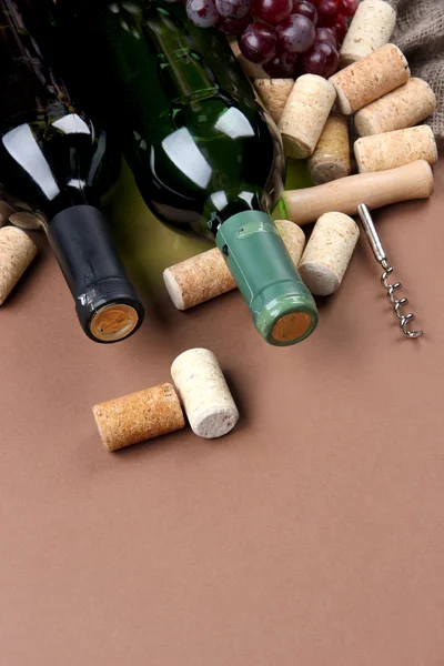 Flessen wijn, druiven en kurken op bruine achtergrond — Stockfoto