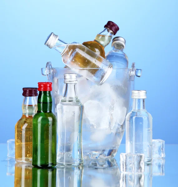 Minibar flessen in emmer met ijsblokjes, op een achtergrond met kleur — Stockfoto