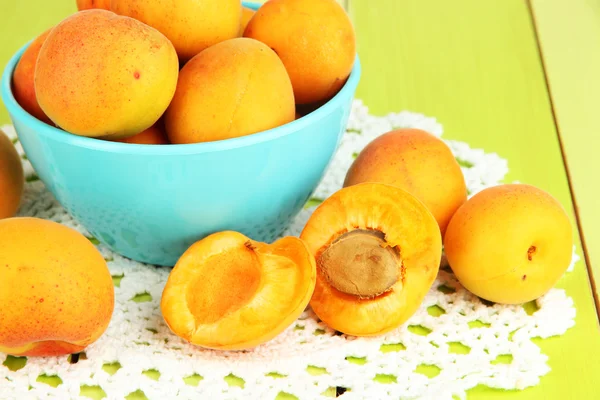 Fresh natural apricot in bowl on green wooden table — Stock Photo, Image