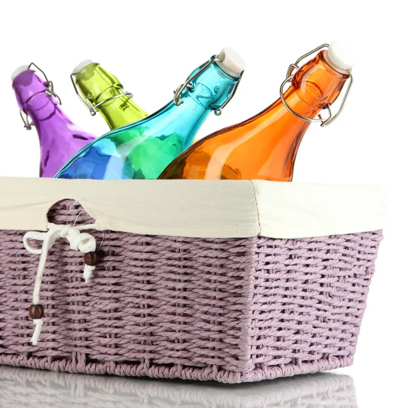 Color glass bottles in wicker basket, isolated on white — Stock Photo, Image