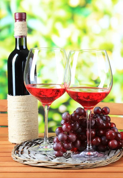 Vasos de vino en bandeja trenzada sobre mesa de madera sobre fondo natural — Foto de Stock