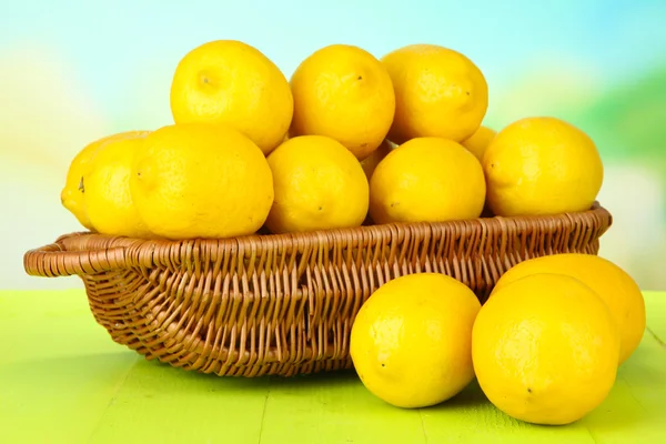 Dojrzałe cytryny w wiklinowym koszu na stole na jasnym tle — Zdjęcie stockowe