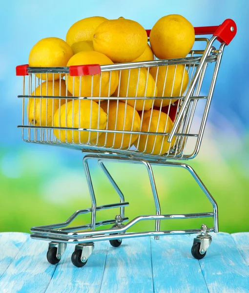Limones maduros en carro sobre mesa sobre fondo brillante —  Fotos de Stock