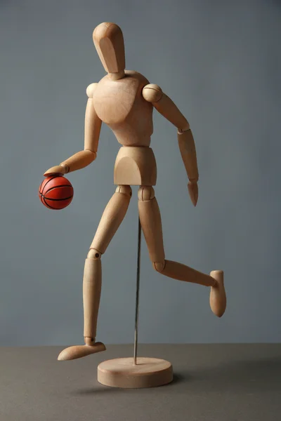 Maniquí de madera con pelota de baloncesto sobre fondo gris — Foto de Stock