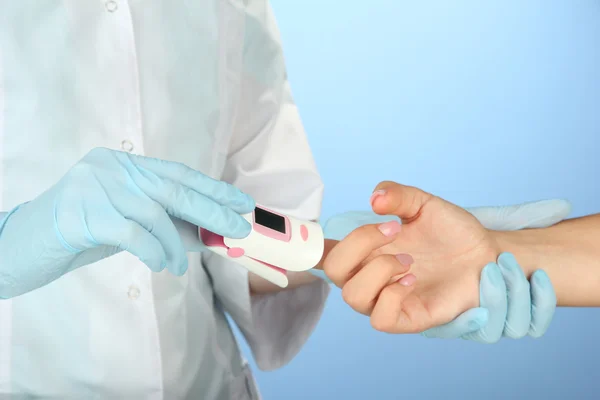 Arzt misst Puls und Sauerstoffgehalt, auf farbigem Hintergrund — Stockfoto