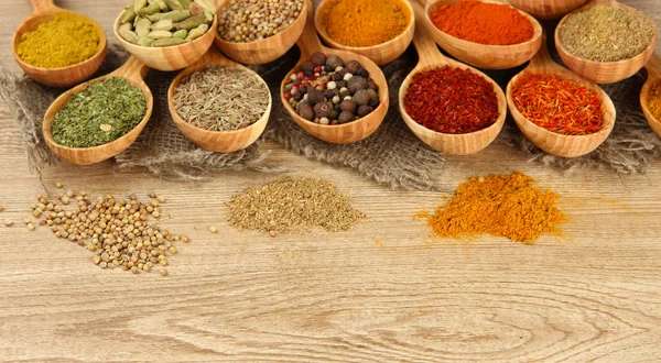 Assortment of spices in wooden spoons on wooden background — Stock Photo, Image