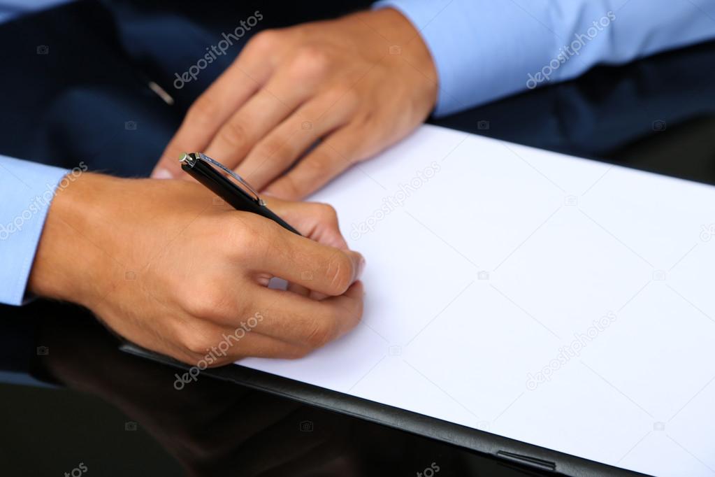 Businessman writing on document in office close-up