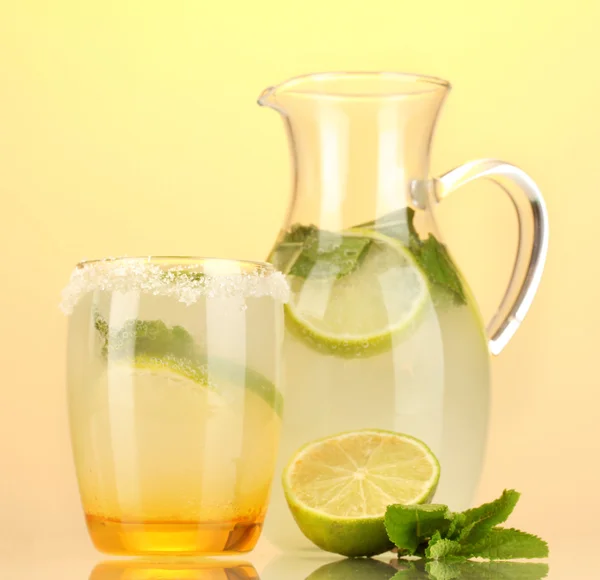 Limonada en jarra y vaso sobre fondo amarillo —  Fotos de Stock