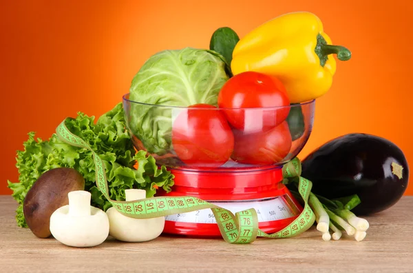 Fresh vegetables in scales on table on orange background — Stock Photo, Image