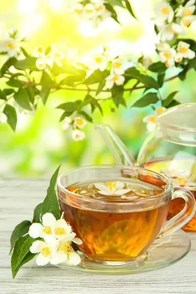 Xícara de chá com jasmim, na mesa de madeira, no fundo brilhante — Fotografia de Stock