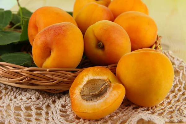 Apricots on wicker coasters on napkin on wooden table — Stock Photo, Image