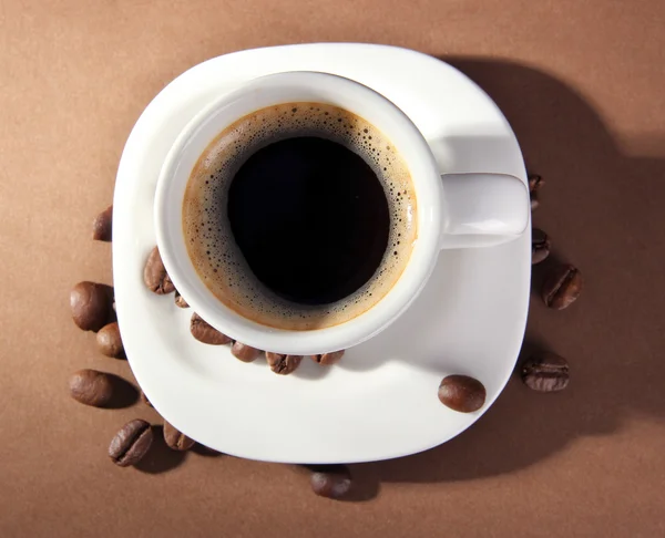 Tasse Kaffee mit Kaffeebohnen auf braunem Hintergrund — Stockfoto