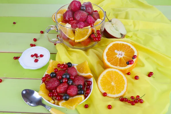 Salada de frutas útil em copo de vidro e tigela em mesa de madeira close-up — Fotografia de Stock