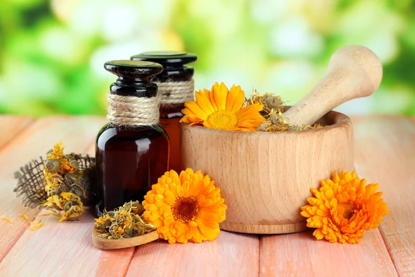 Geneeskundeflessen en calendula bloemen op houten tafel — Stockfoto