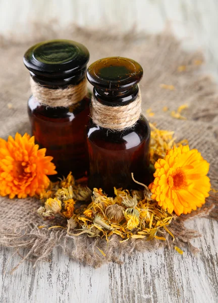 Bottiglie di medicina e fiori di calendula su sfondo di legno — Foto Stock