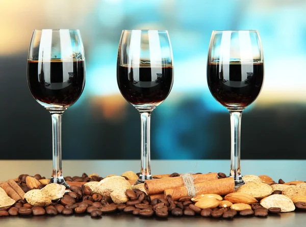 Glasses of liquors with almonds and coffee grains, on bright background — Stock Photo, Image