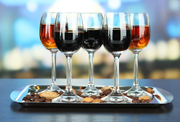 Glasses of liquors with almonds and coffee grains, on tray, on bright background — Stock Photo, Image