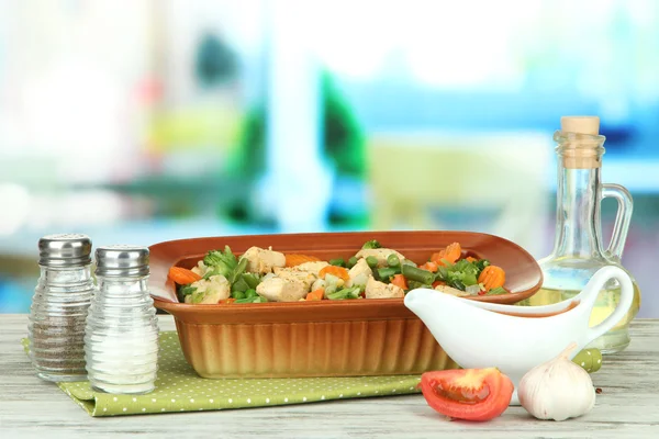 Casseruola con verdure e carne, su tavolo di legno, su sfondo brillante — Foto Stock