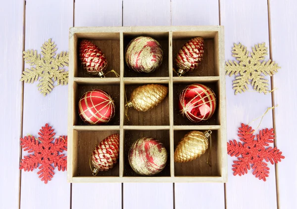 Holzkiste gefüllt mit Weihnachtsschmuck, auf farbigem Holzgrund — Stockfoto