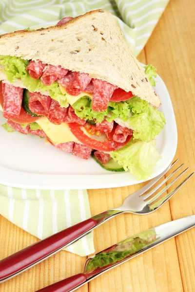 Huge sandwich on wooden table, on wooden background — Stock Photo, Image