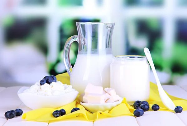 Čerstvé mléčné výrobky s borůvkovým na dřevěný stůl na pozadí okna — Stock fotografie