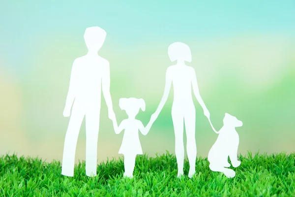 Familie aus Papier auf Gras auf hellem Hintergrund lizenzfreie Stockbilder