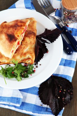 Pizza calzones tabakta üzerine peçete ahşap masa üzerinde