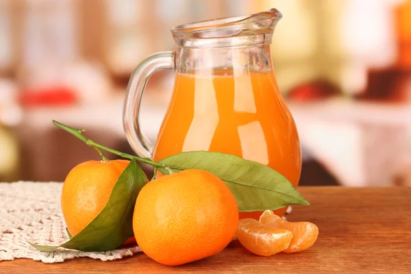 Full jug of tangerine juice, on wooden table on bright background — Stock Photo, Image