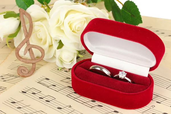 Treble clef, roses et boîte tenant des alliances sur fond musical — Photo