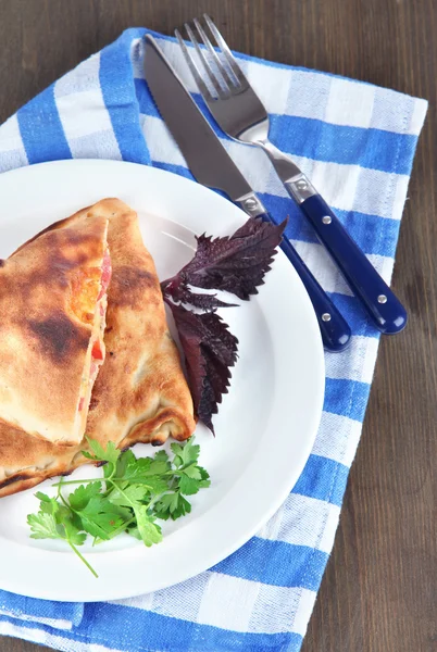 Pizza calzones tabakta üzerine peçete ahşap masa üzerinde