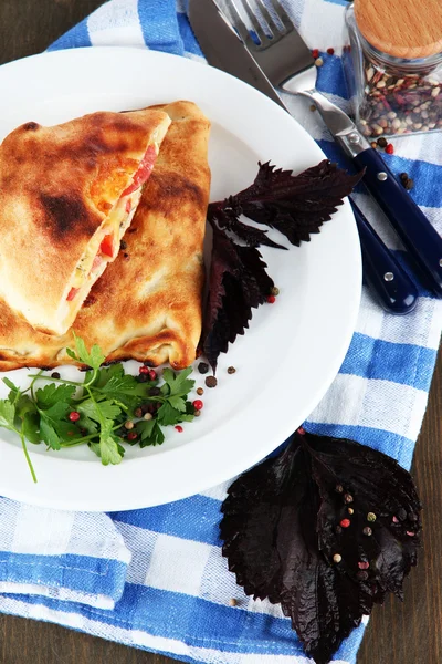 Pizza calzoni su piatto su tovagliolo su tavolo di legno — Foto Stock