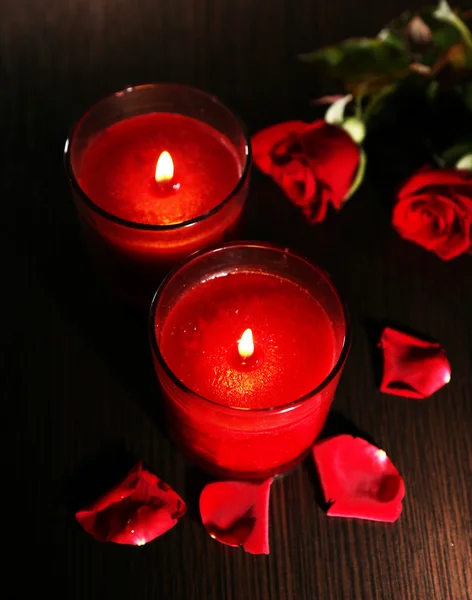 Belas velas vermelhas românticas com pétalas de flores no fundo de madeira escura — Fotografia de Stock