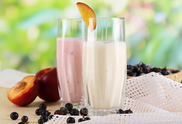 Вкусные молочные коктейли с ежевикой и персиком на деревянном столе на естественном фоне — стоковое фото
