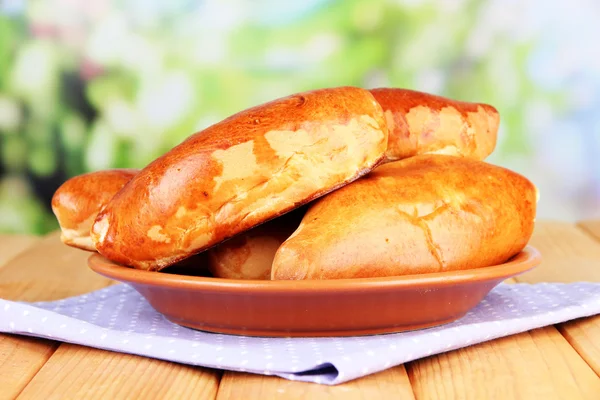 Fresh baked pasties, on wooden table, on bright background — Stock Photo, Image