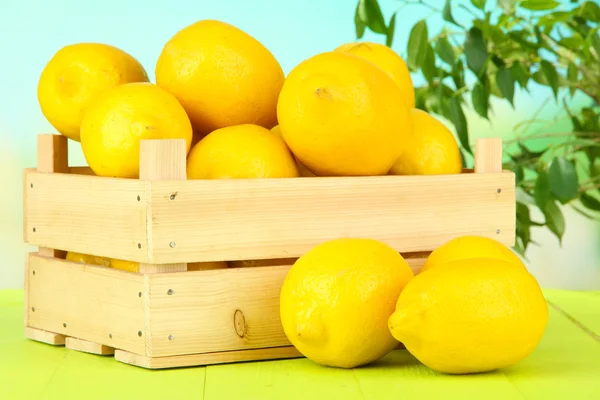 Ripe lemons in wooden box on table on bright background — Stock Photo, Image