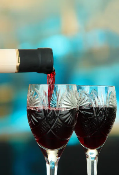 Vin rouge versé dans un verre à vin, sur fond lumineux — Photo