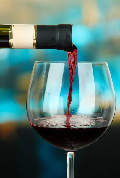 Vin rouge versé dans un verre à vin, sur fond lumineux — Photo