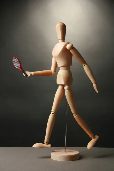 Деревянный манекен с теннисной ракеткой на сером фоне — стоковое фото