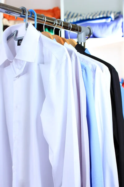 Variedad de camisas casuales en perchas de madera en los estantes de fondo —  Fotos de Stock