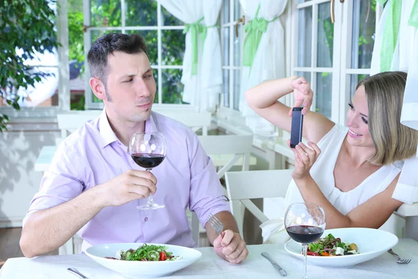 Casal jovem tirando foto com telefone celular no restaurante — Fotografia de Stock