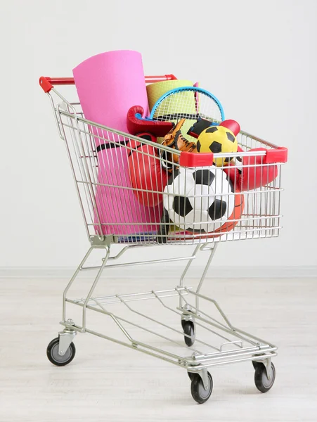 Shopping cart with sport equipment, on gray background — Stock Photo, Image