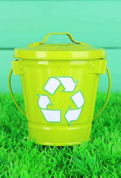 Recycling-Tonne auf grünem Gras auf hölzernem Hintergrund — Stockfoto